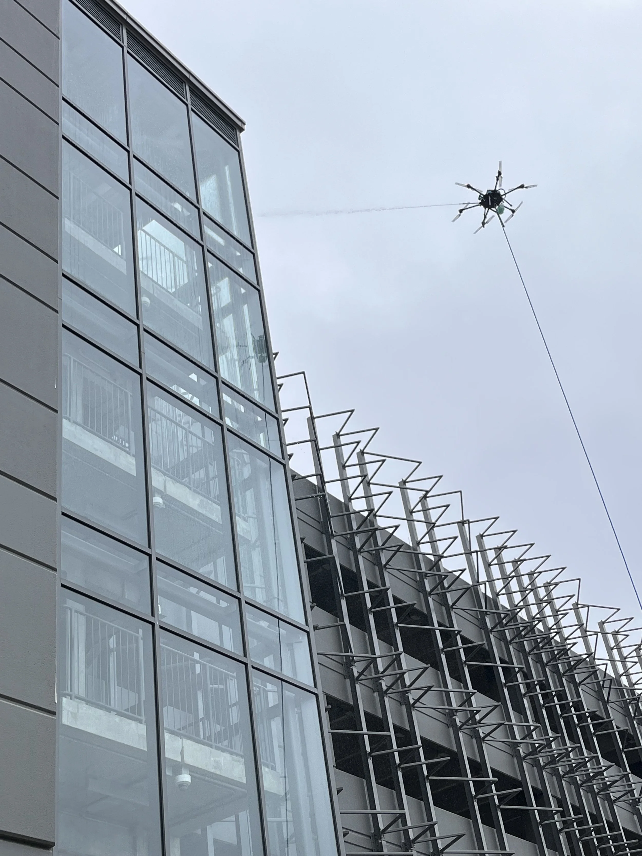 Cleaning drone flying beside the glass facade of a multi-story commercial building