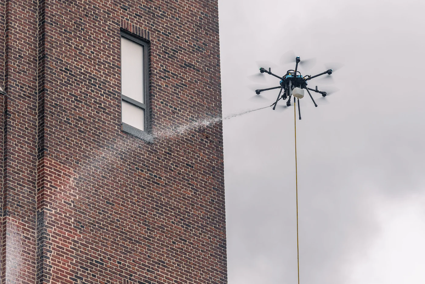 Cleaning drone softwashing the brick facade of the Domino Sugar refinery in Baltimore