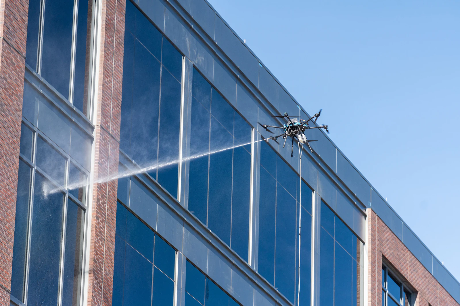 Cleaning drone washing the upper-story glass of a commercial building